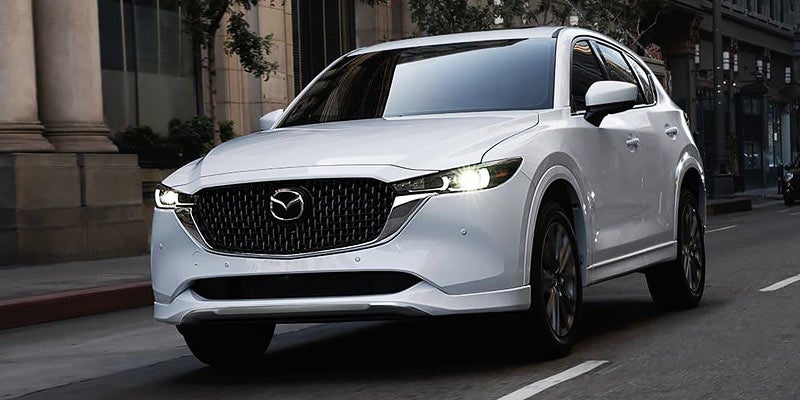 white mazda cx5 driving down a city street