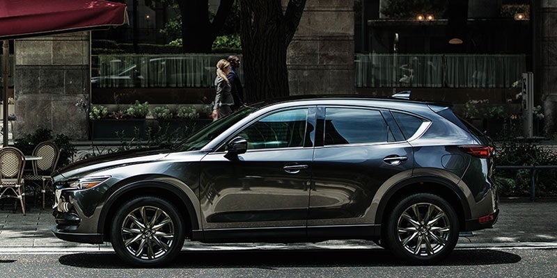 The side profile of a 2020 Mazda CX-5 parked in front of a building.